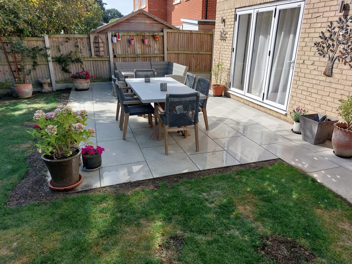 Finished patio dining area beside a house and lawn