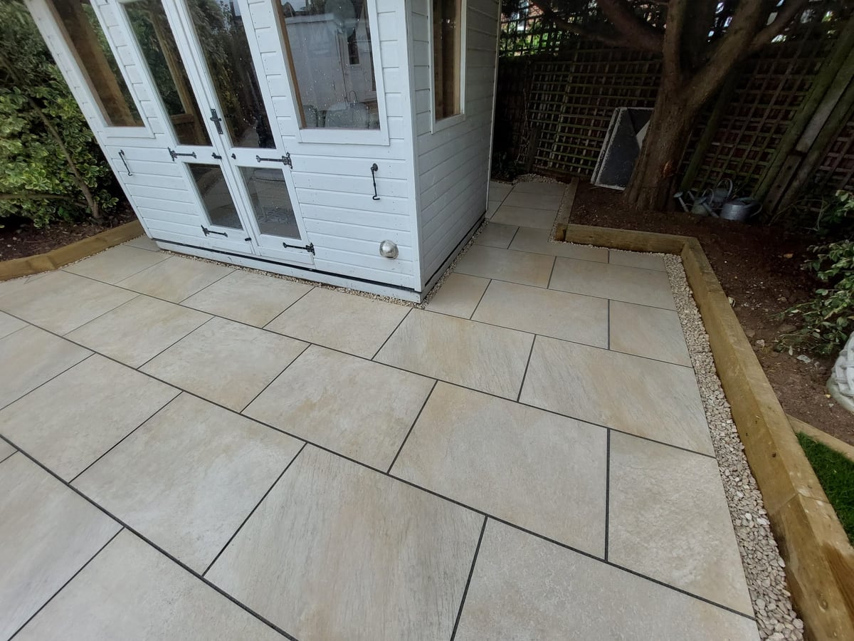 Finished paved area around a garden shed and trellis fence
